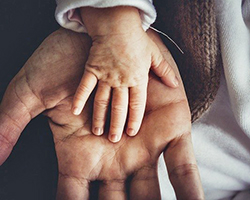 A baby's hand resting on an adult's hand.