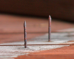 A rusty nail poking up out of a board of wood