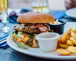 A picture of a hamburger on a plate with a side of fries at a restaurant