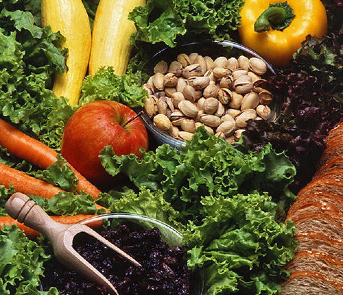 Una fotografía de una variedad de frutas, verduras, nueces y pan sobre una cama de lechuga