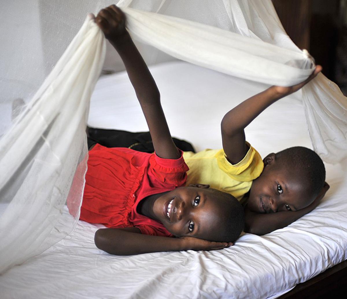 Two children peeking out from under their bed net in Tanzania.