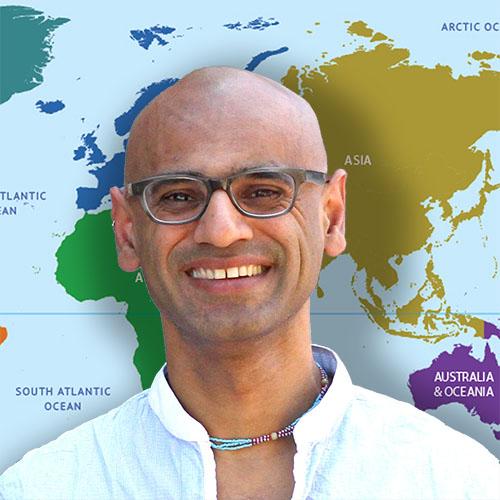 Arvind Varsani in front of a world map.